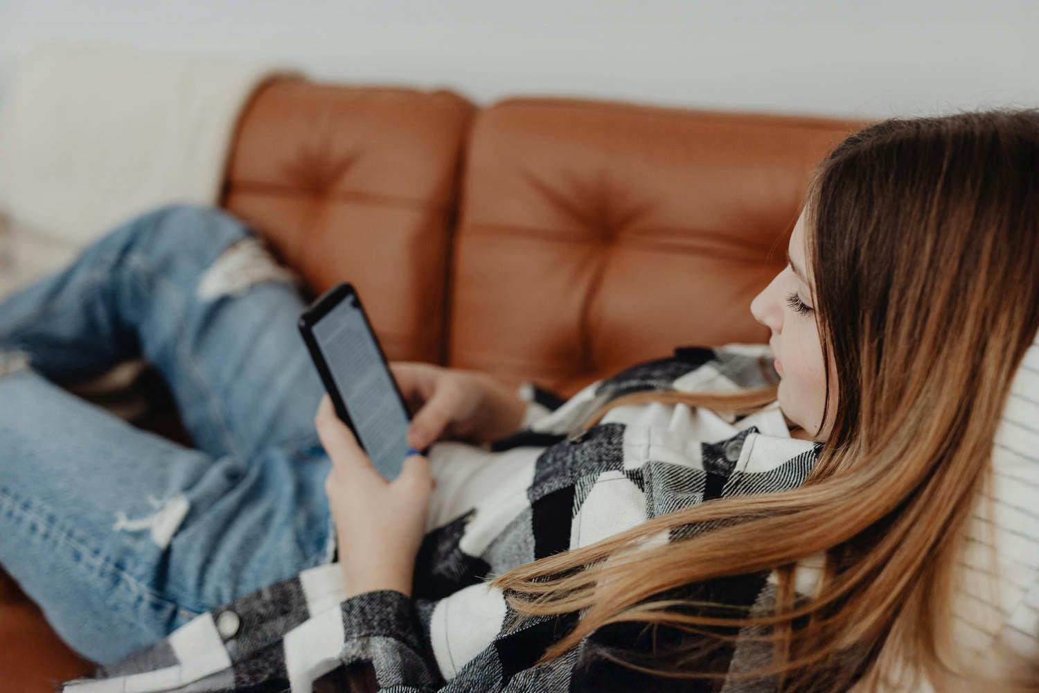 Przeglądanie smartfona na kanapie przez młodą kobietę