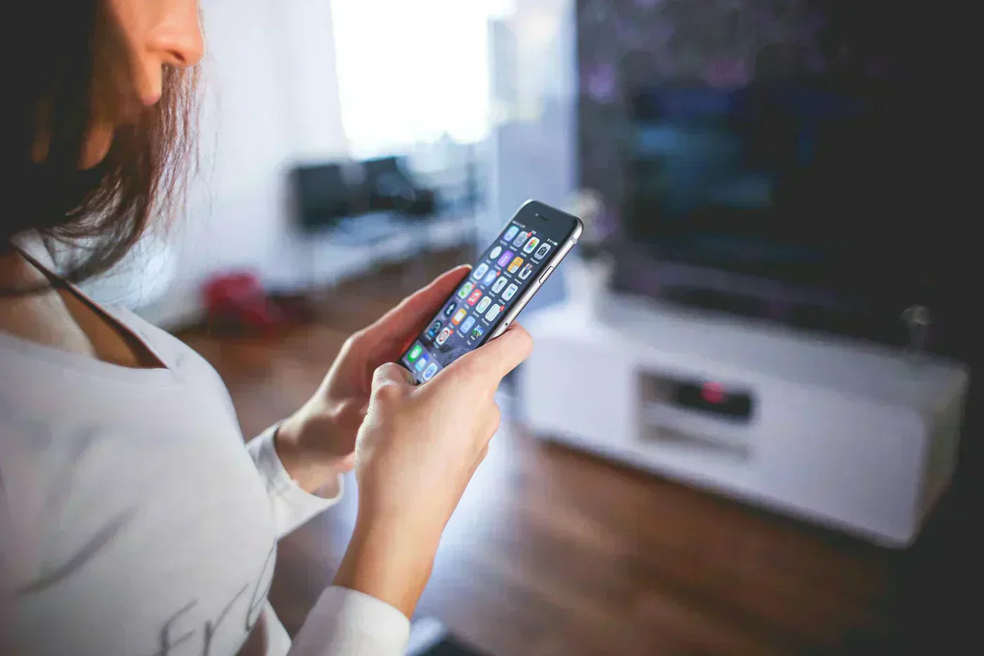 Kobieta trzymająca telefon w ręce i przeglądająca aplikacje w smartfonie.